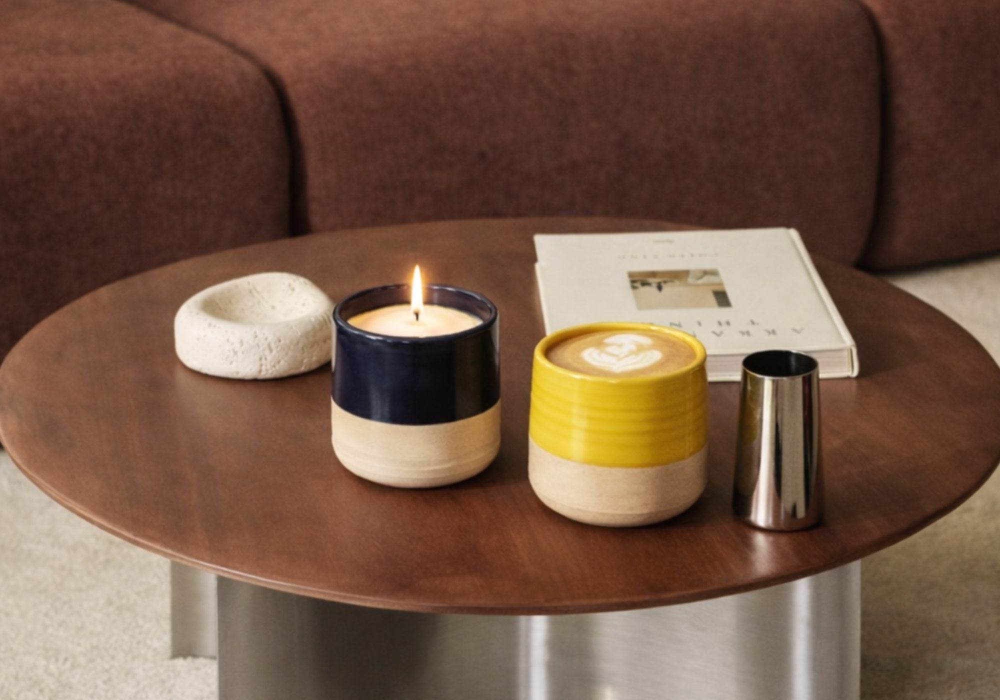 Bougie parfumée Maison Tassan en céramique posée sur une table basse avec café et livre dans un intérieur moderne et chaleureux.