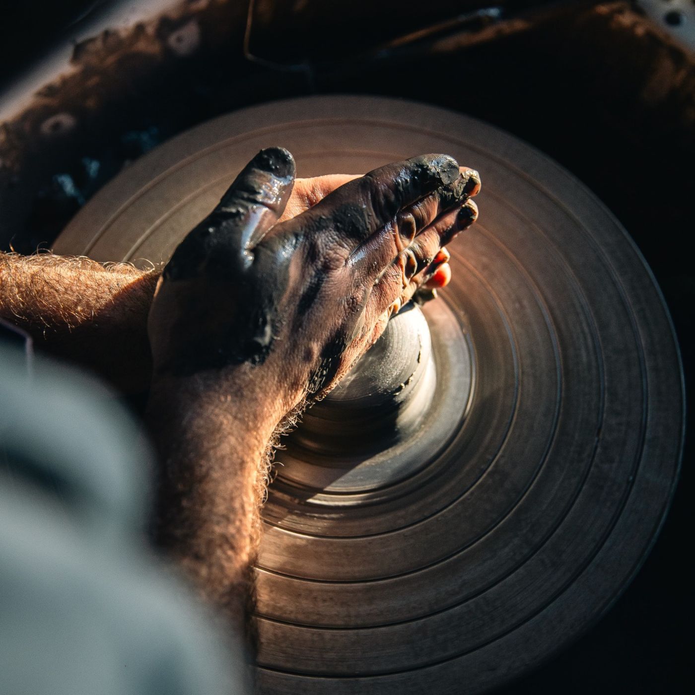 Mains d’un artisan travaillant l’argile sur un tour de potier pour créer une pièce en céramique artisanale Maison Tassan.
