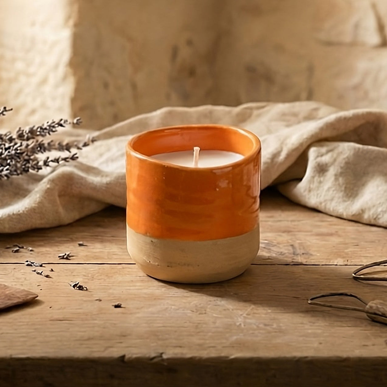 Grande bougie céramique artisanale rechargeable à trois mèches, pot bicolore crème et naturel, posée sur une table en bois avec du lin et de la lavande pour une ambiance chaleureuse en Provence.